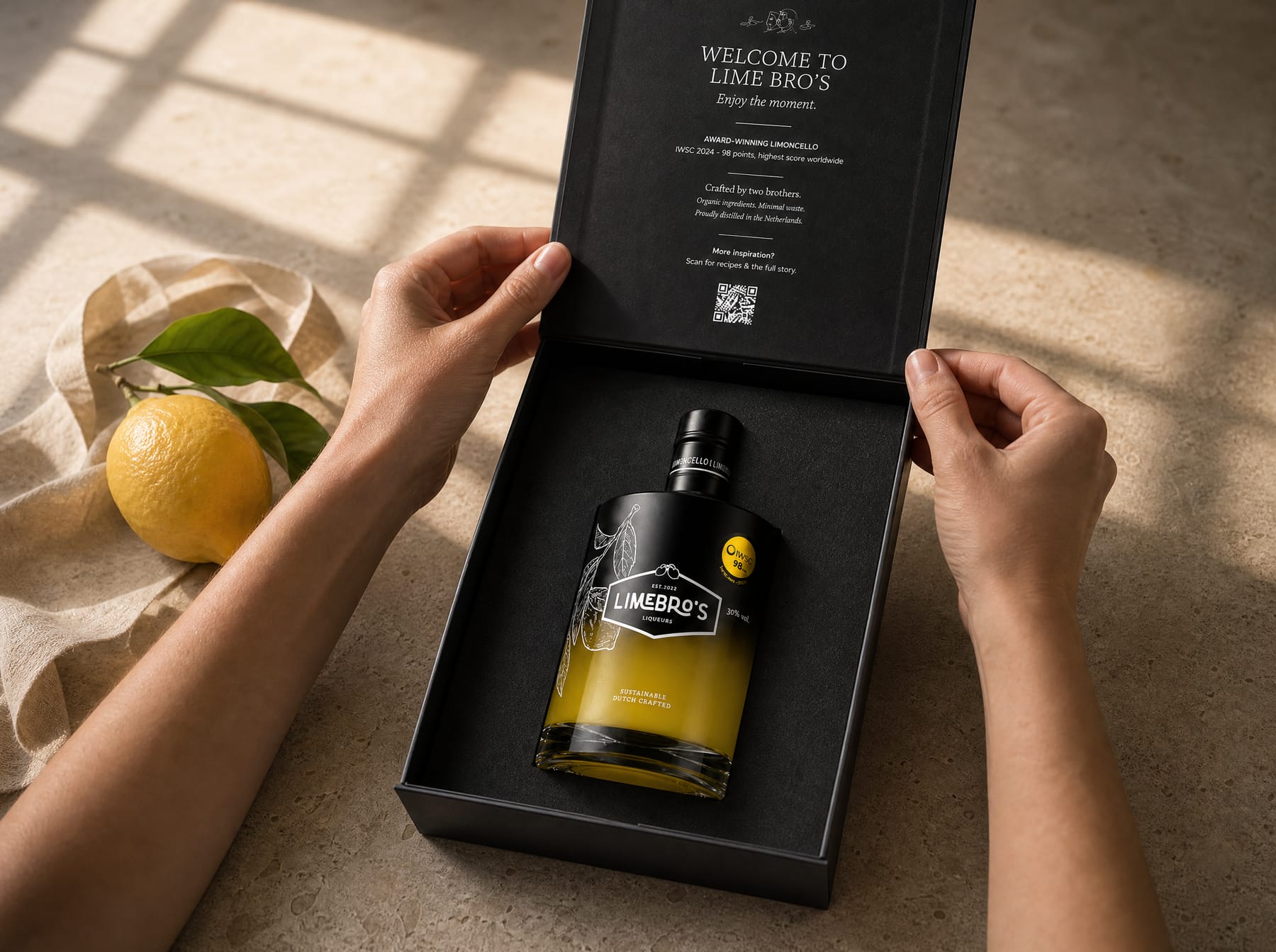 Handen openen een zwarte Lime Bro's geschenkdoos met daarin een fles limoncello